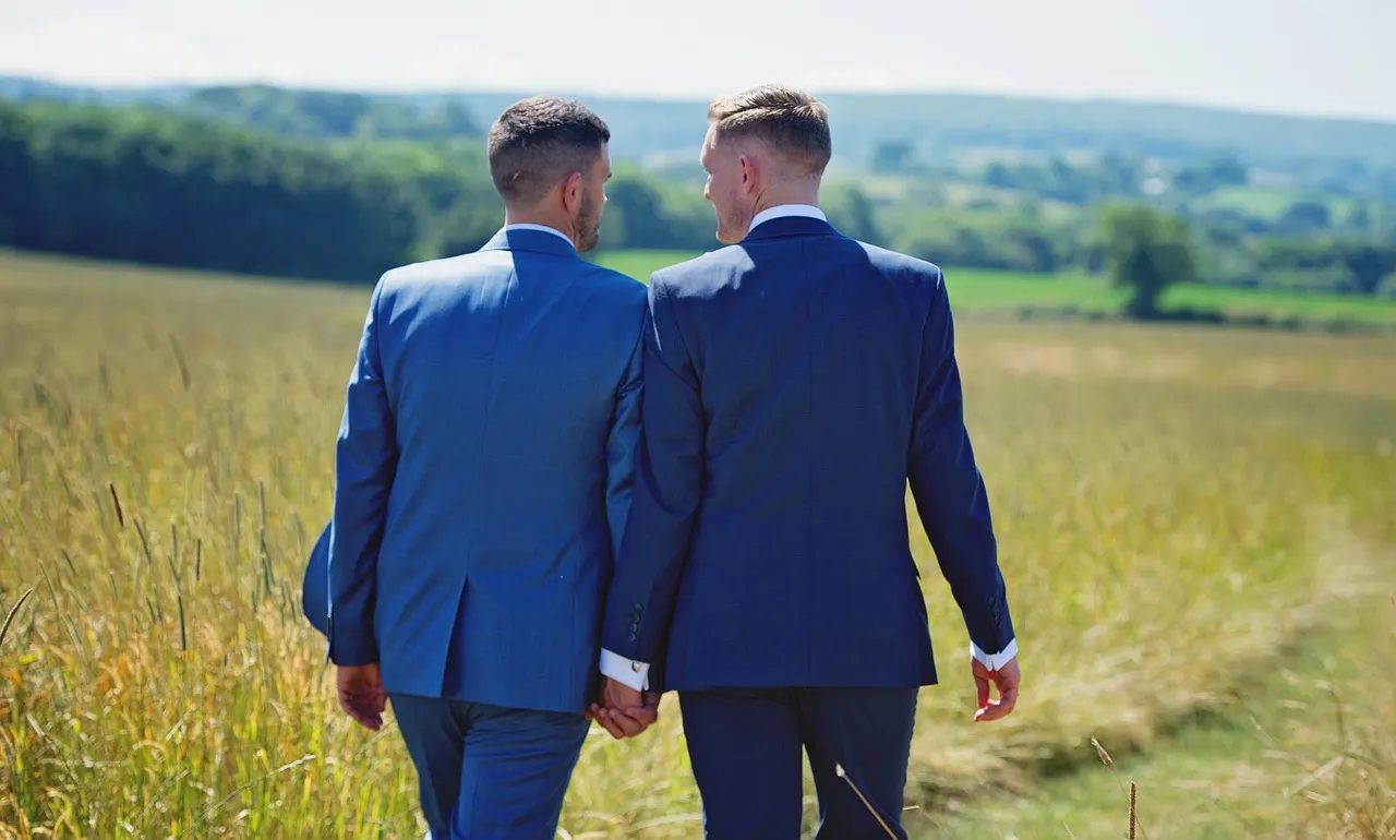 Two people walking together through a sunlit field